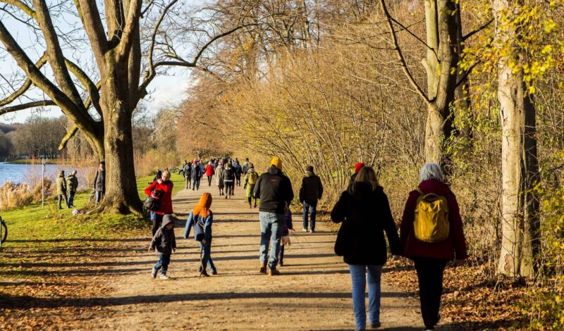 Spaziergänger sind bei strahlendem Sonnenschein und kalten Temperaturen am Decksteiner Weiher im Grüngürtel in Köln-Sülz unterwegs.