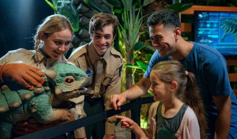 Besucher mit Mitarbeitern bei der Jurassic World Ausstellung