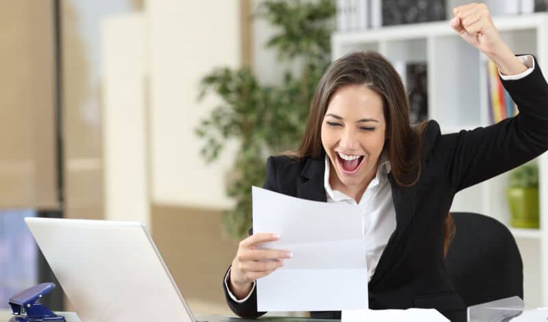 Frau am Schreibtisch freut sich sehr.