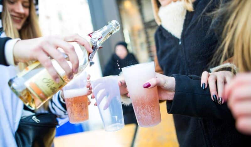 Karnevalisten schenken sich Sekt in Plastikbecher ein