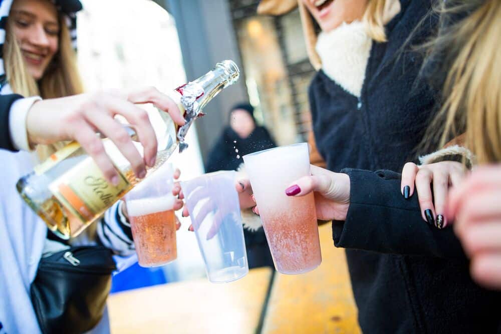 Karnevalisten schenken sich Sekt in Plastikbecher ein