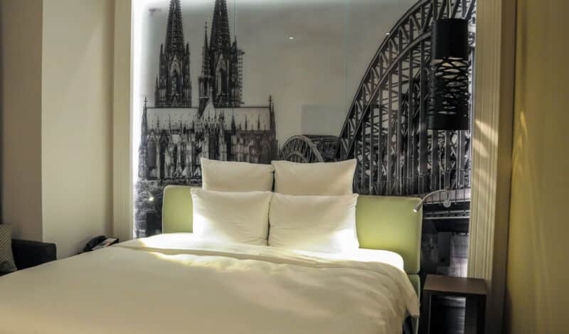 Hotelzimmer mit Doppelbett und Kölnpanorama.