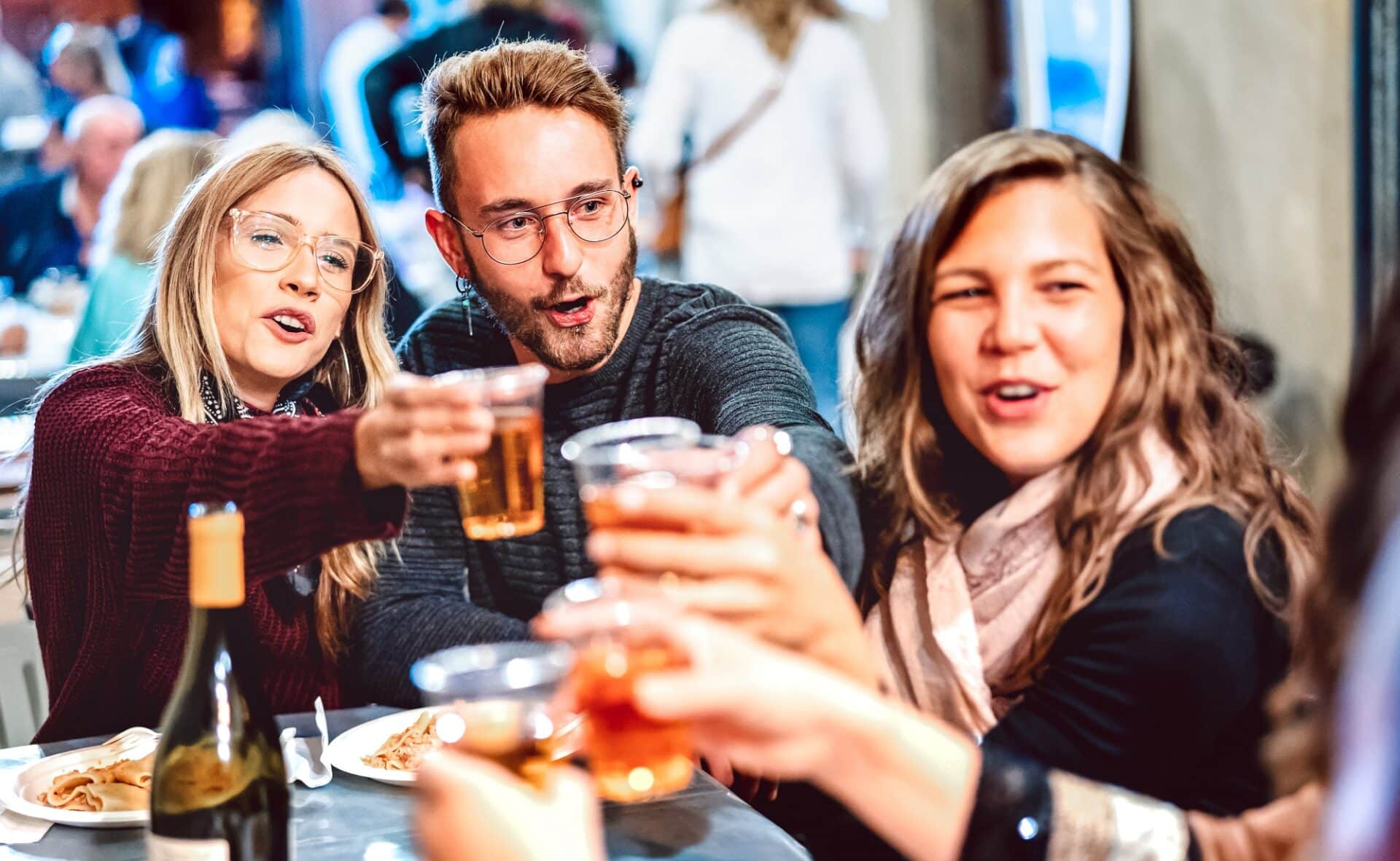 Junge Leute stoßen mit Bechern Bier an.