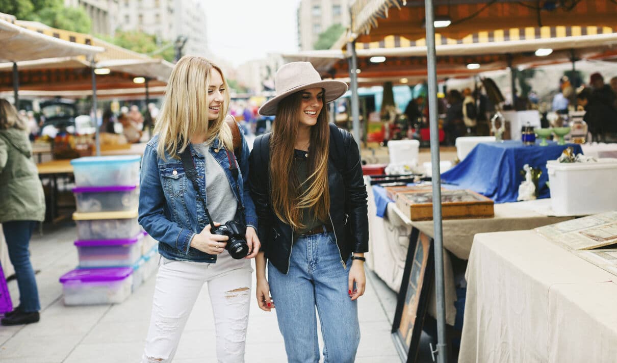 Junge Frauen bummeln über einen Flohmarkt