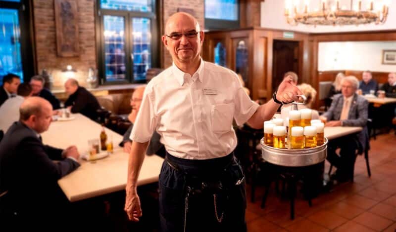 Köbes im Brauhaus mit einem Kranz Kölsch