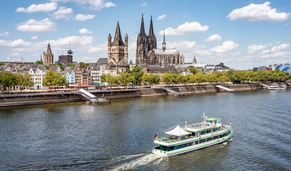 Ein Schiff fährt vor der Kölner Altstadtkulisse mit Dom rheinabwärts