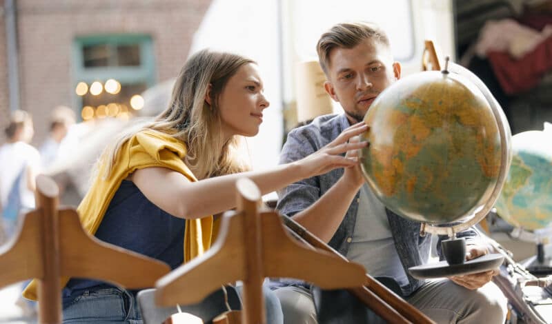 Ein Mann und eine Frau betrachten einen Globus auf einem Flohmarkt