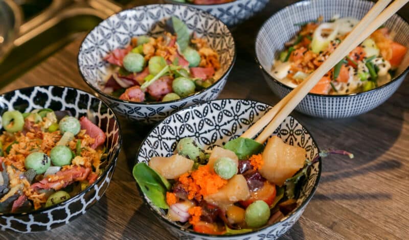 Bowls mit Thunfisch und anderen Zutaten, die mit Stäbchen gegessen werden.
