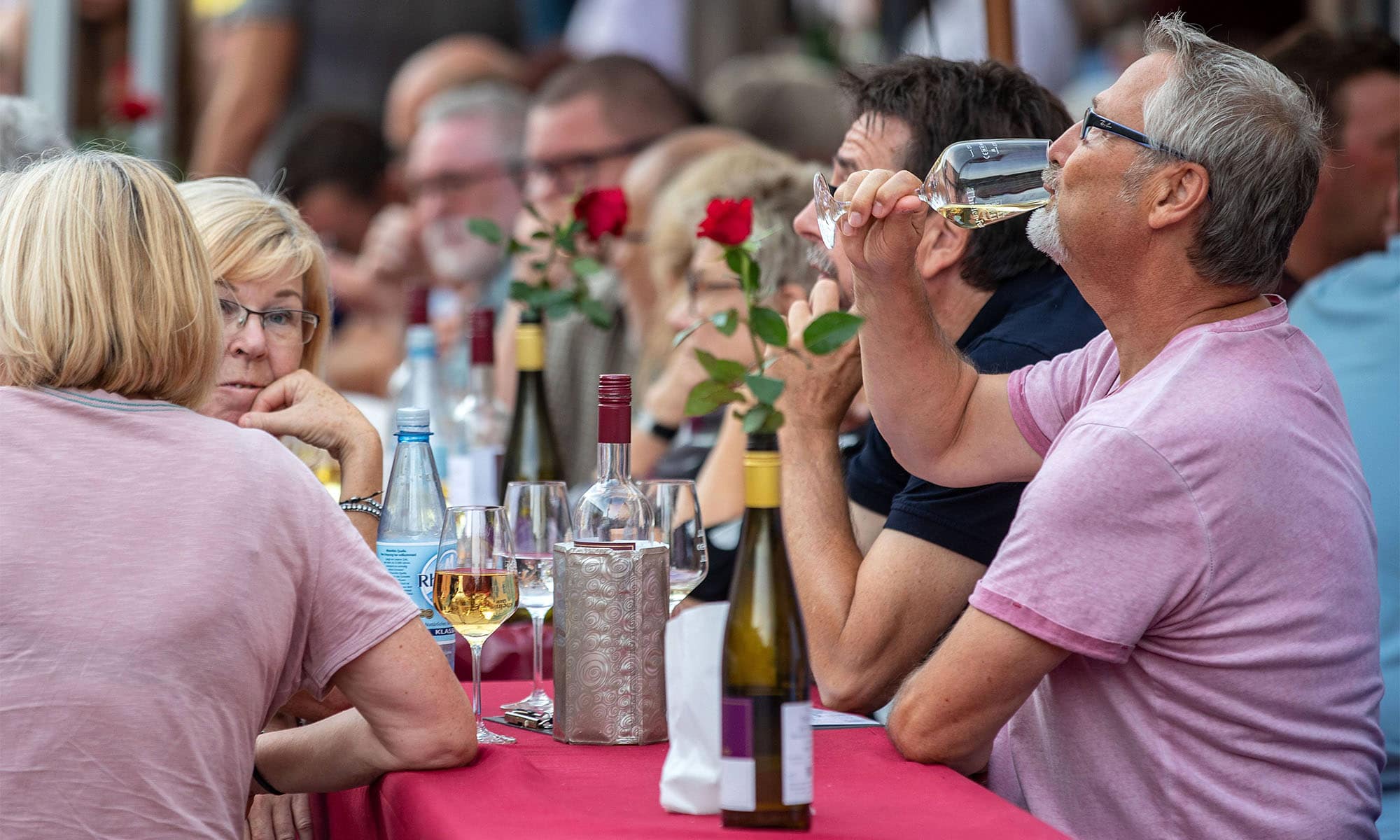 Ein Mann trinkt Weißwein auf einem Weinfest.