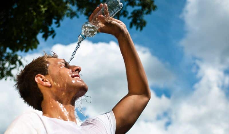 Sportler kühlt sich mit Wasser ab