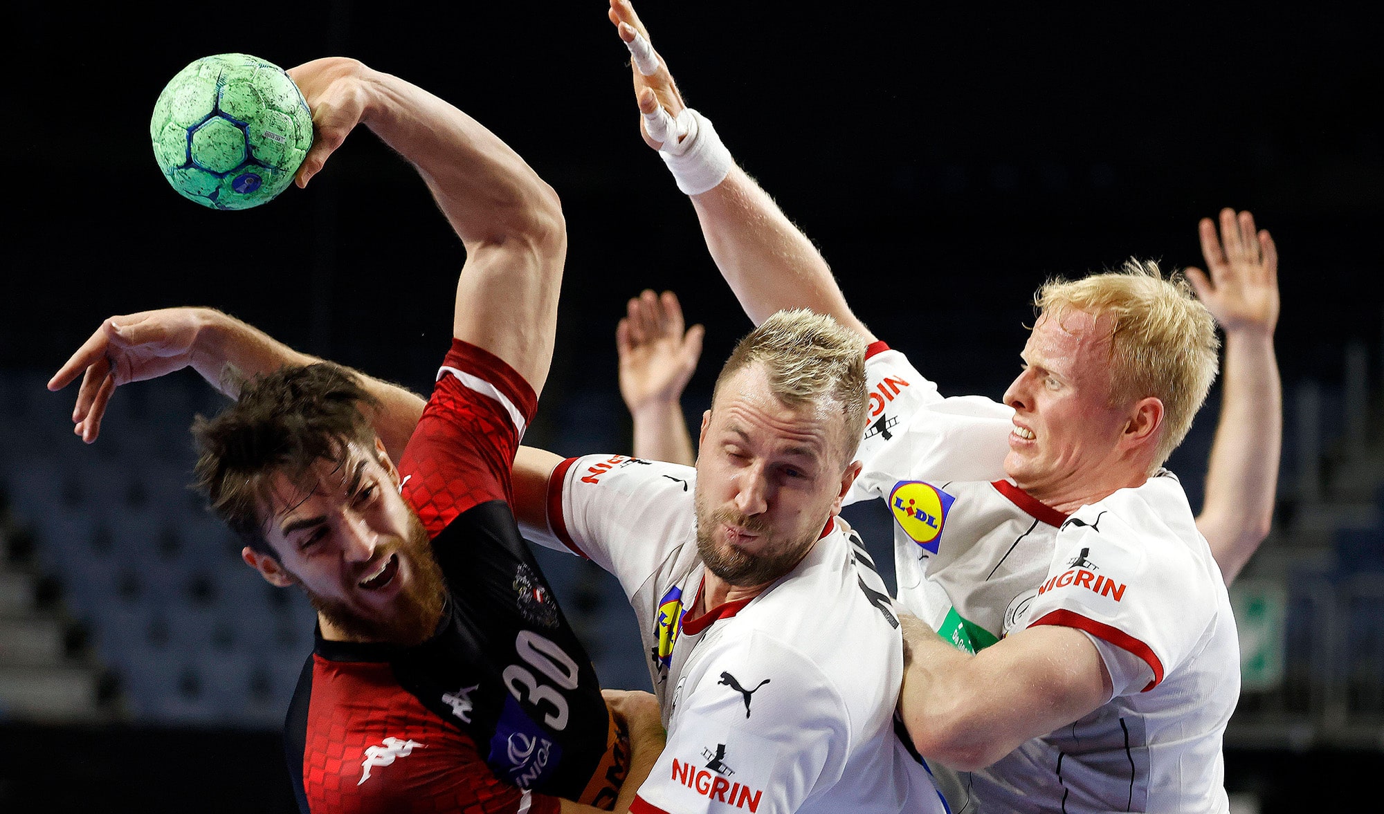 Das Foto zeigt drei Spieler bei einem Handballspiel in der Kölner Lanxess-Arena.