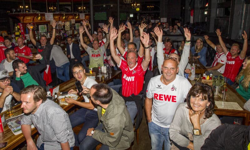 Fans des 1. FC Köln feiern in einer Fußballkneipe