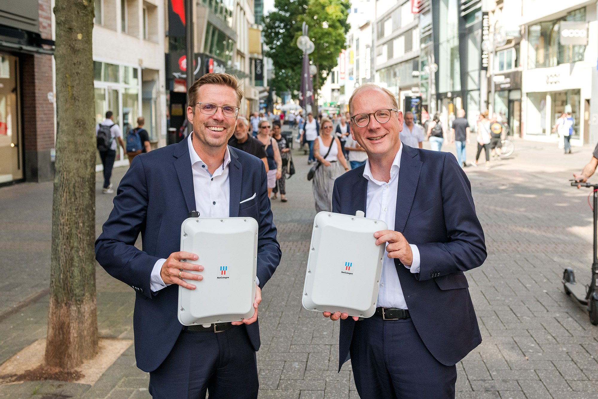 Das Bild zeigt Andree Haack und Timo von Lepel mit zwei WLAN-Hotspots in der Kölner Innenstadt.