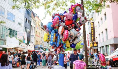 Das Foto zeigt einen Verkäufer mit vielen Luftballons bei einem Straßenfest in Köln.