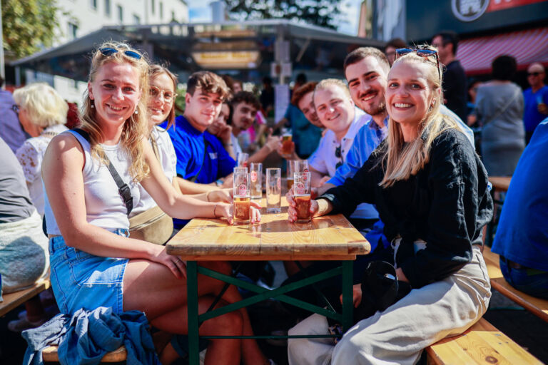 Das Foto zeigt Besucher eines Veedelsfests an einem Biertisch.