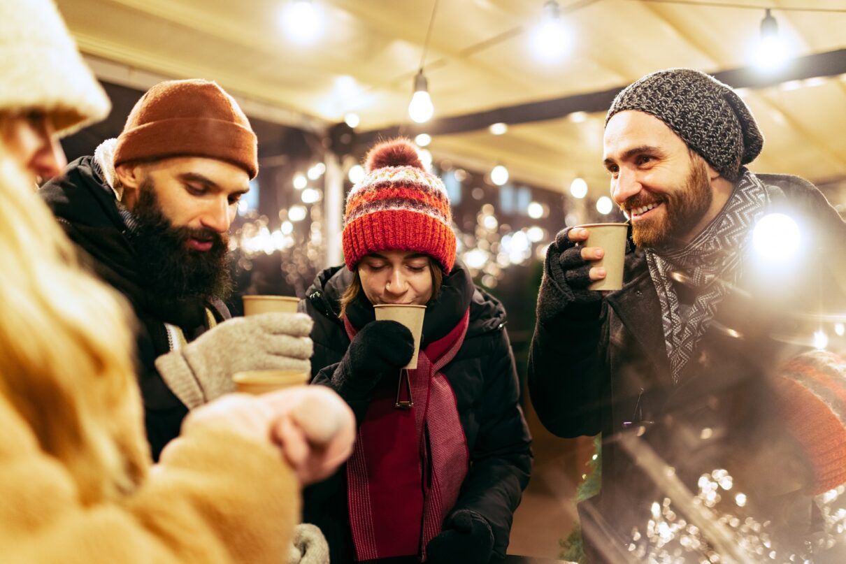 Freunde trinken Glühwein auf Weihnachtsmarkt