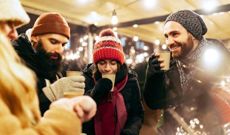 Freunde trinken Glühwein auf Weihnachtsmarkt
