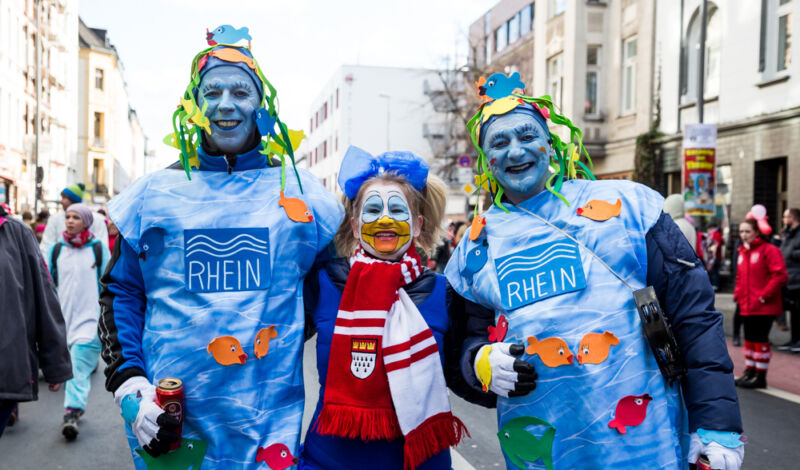 Das Foto zeigt drei als der Fluss Rhein verkleidete Jecken wärhend des Karnevalsumzugs in Ehrenfeld.