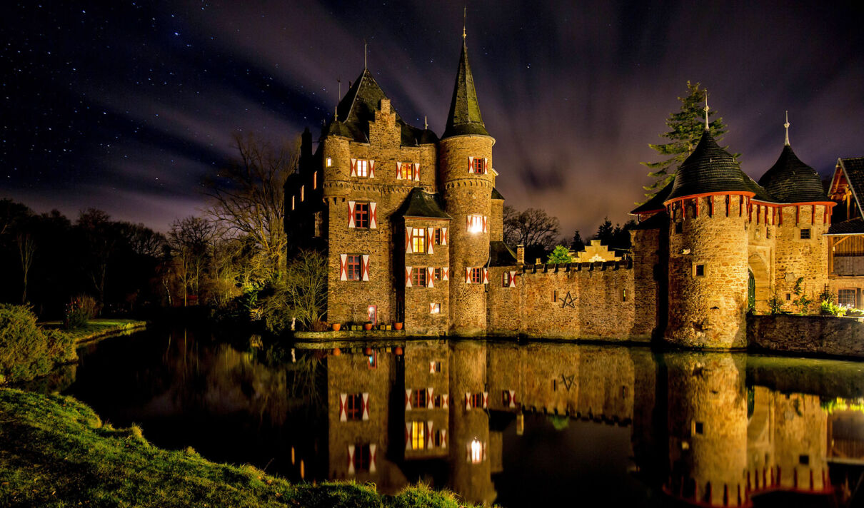 Beleuchtete Burg Satzvey in der Eifel bei Nacht.
