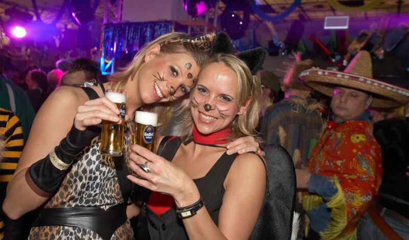 Zwei junge und verkleidete Frauen feiern Karneval in einer Kneipe