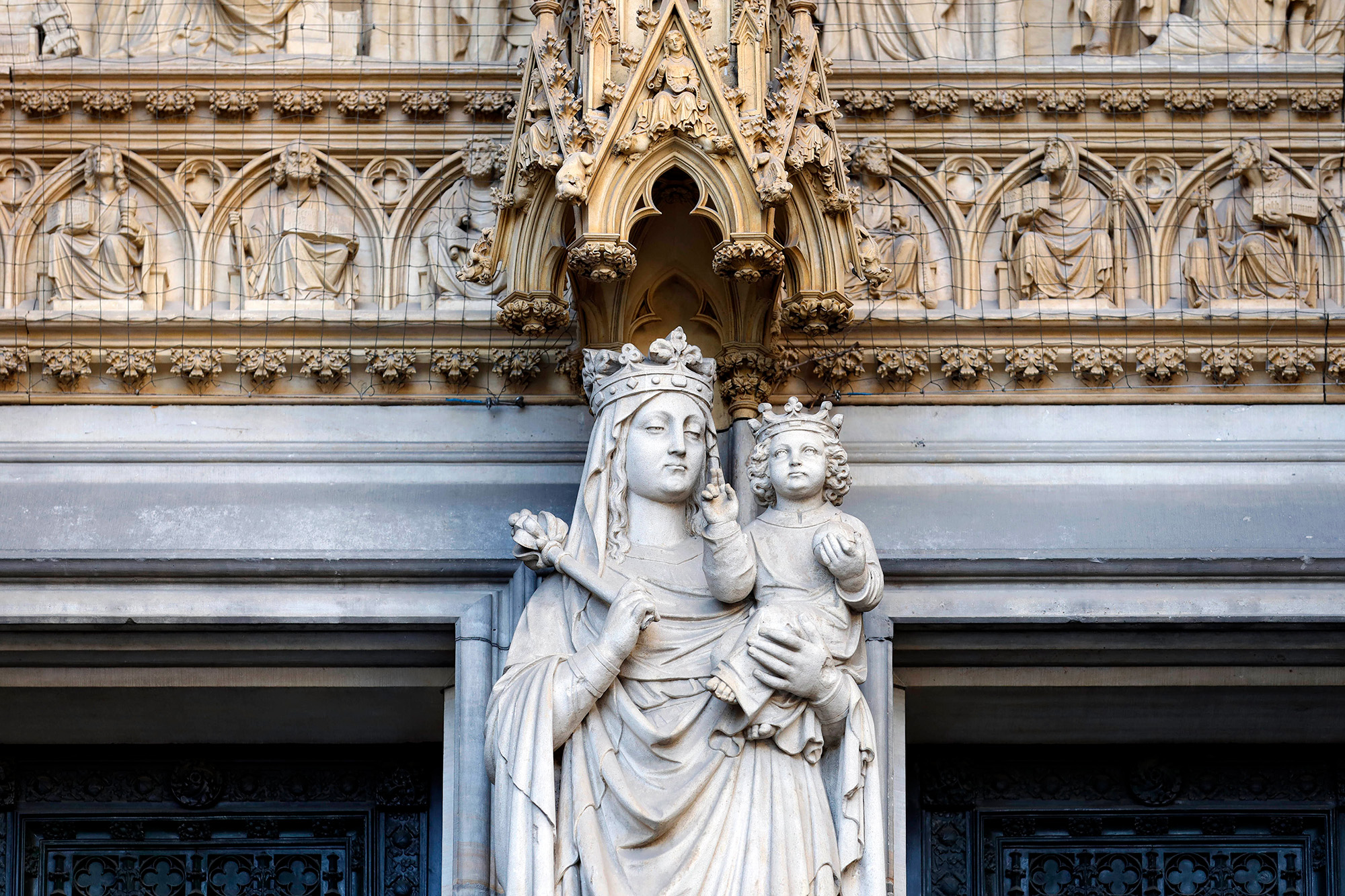 Das Foto zeigt die Kalkstein-Figuren der Heiligen Maria mit Jesuskind am Mittelpfeiler des Hauptportals des Kölner Doms.