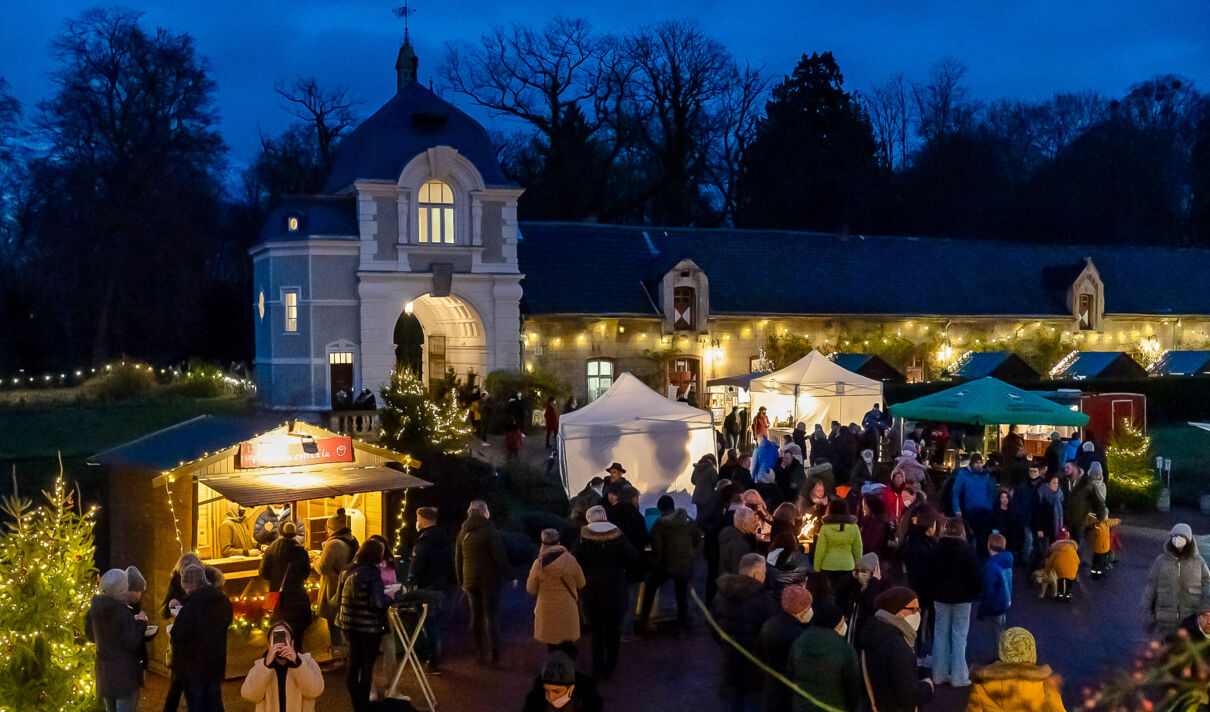 Besucher des Weihnachtsmarktes auf Schloss Türnich in der Dämmerung.