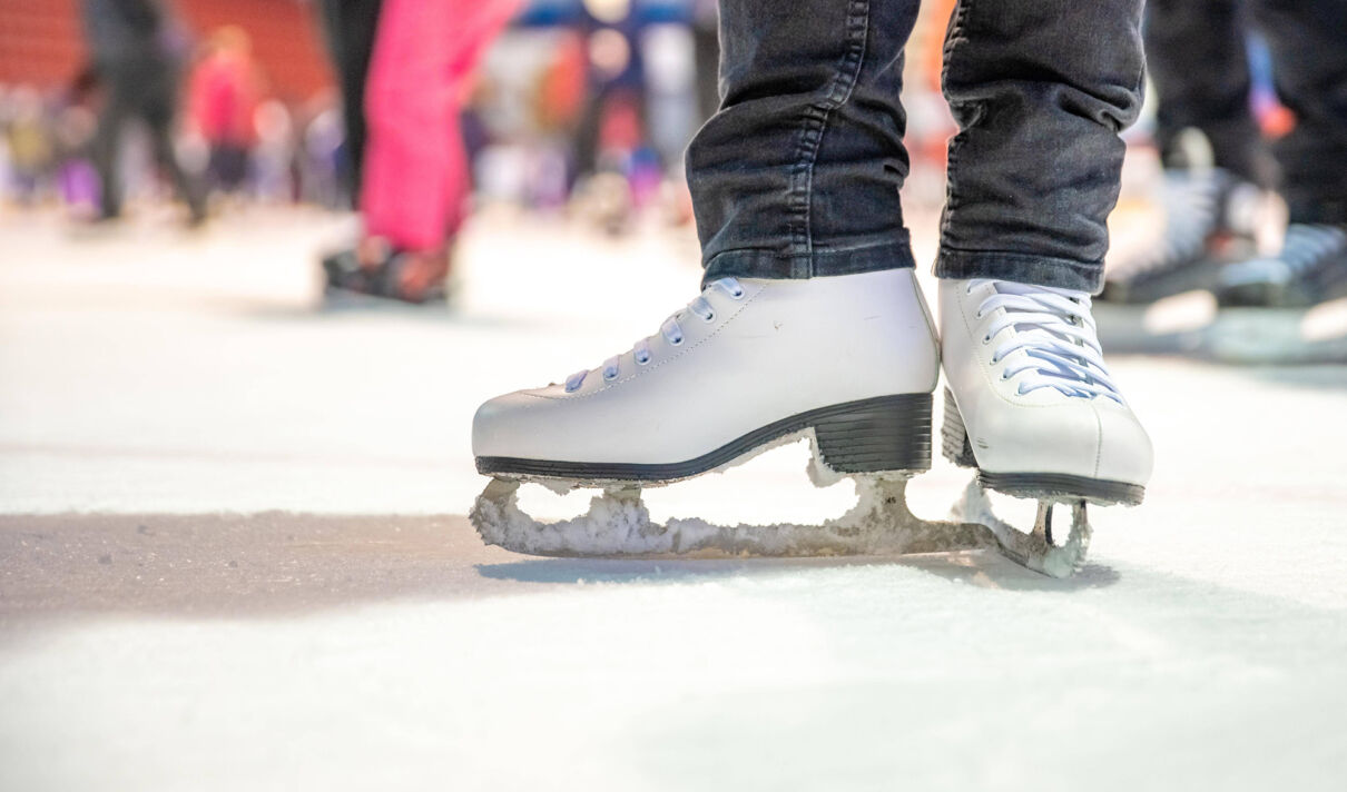 Das Foto zeigt ein Paar weiße Schlittschuhe auf einer Eisfläche.