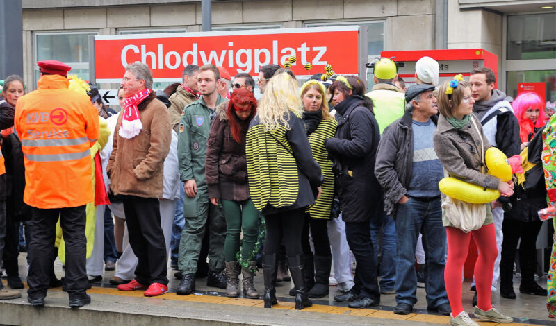 Karnevalisten stehen in Köln an der KVB-Haltestelle "Chlodwigplatz"