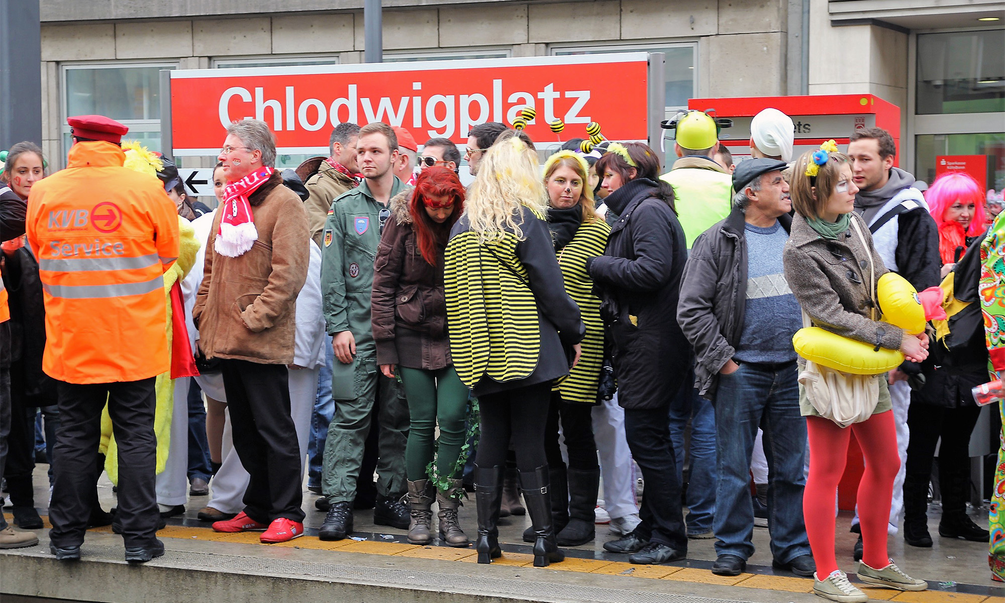Karnevalisten stehen in Köln an der KVB-Haltestelle "Chlodwigplatz"