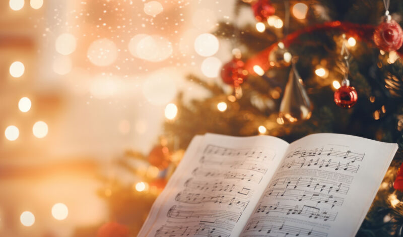 Im Vordergrund ein Notenblatt, im Hintergrund ein geschmückter Weihnachtsbaum
