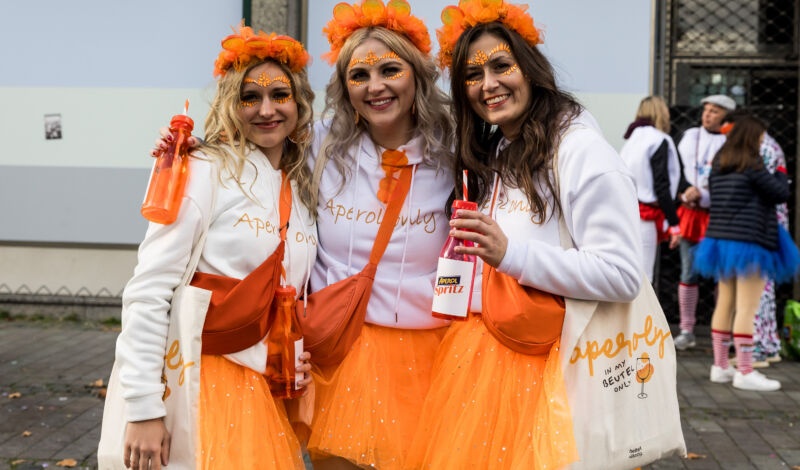 Drei Frauen posieren im Aperol Spritz Kostüm.