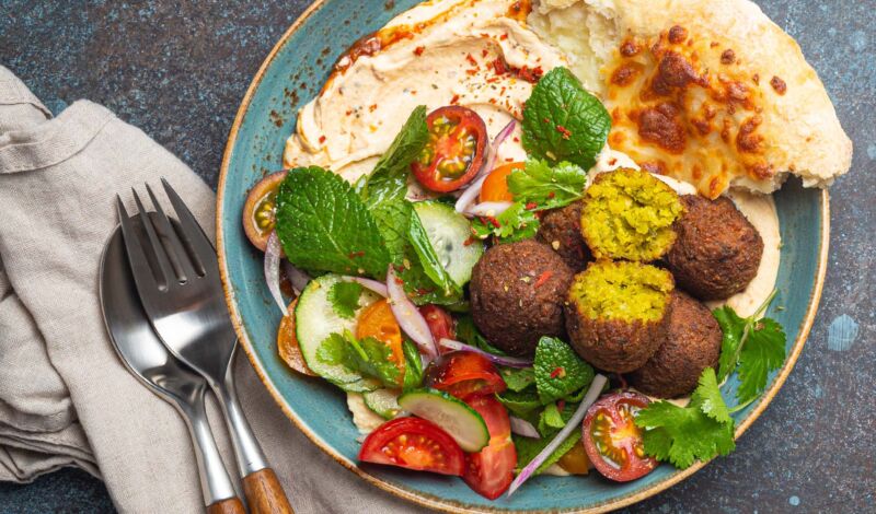 Falafelbällchen mit Salat zusammen mit Hummus und einem Fladenbrot auf einem Teller