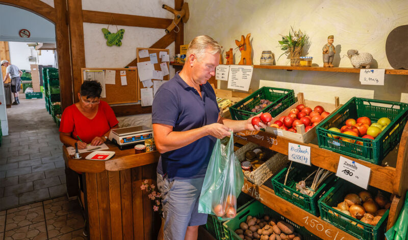 Ein Mann kauft in einem Hofladen Obst und Gemüse ein.