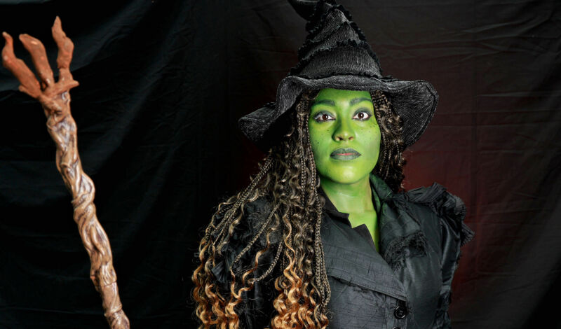 Eine Frau, verkleidet als Elphaba, die böse Hexe des Westens, aus dem Musical Wicked mit grünem Gesicht.