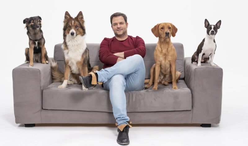 Martin Rütter mit Hunden auf einem Sofa sitzend