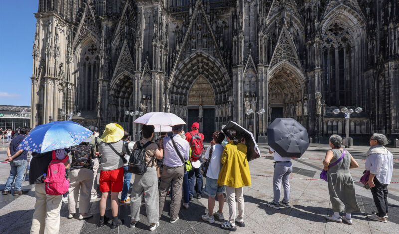 Eine Gruppe von Touristen aus Asien steht vor dem Kölner Dom