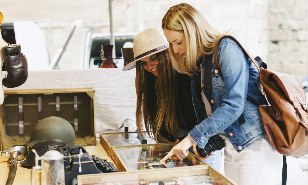 Zwei junge Frauen schlendern über einen Flohmarkt
