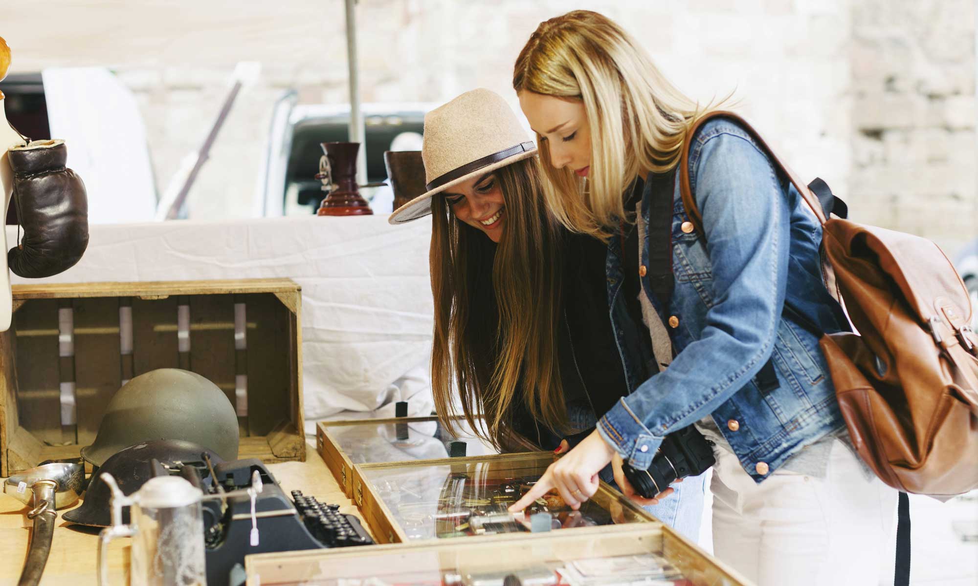 Zwei junge Frauen schlendern über einen Flohmarkt