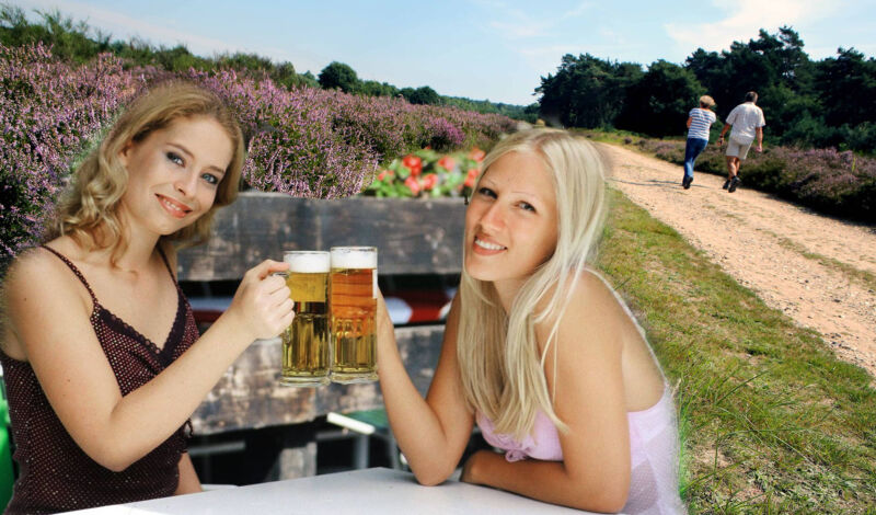 Zwei Frauen stoßen in einem Ausflugslokal mit einem Bier an.