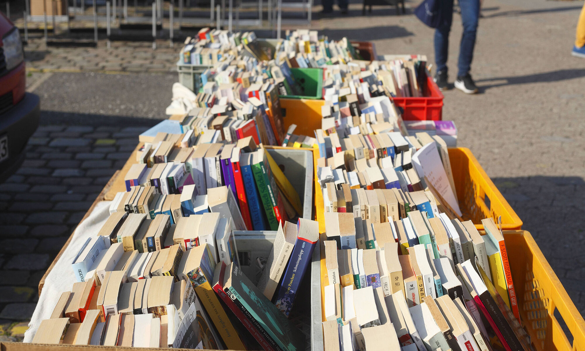 Bücher-Flohmarkt in Köln-Riehl Das Bild zeigt aufgestapelte Bücher auf einem Flohmarkt.