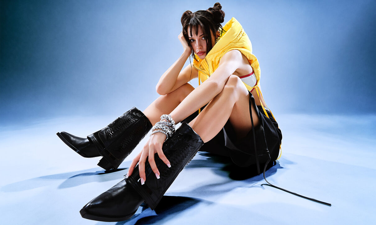 Rapperin Nina Chuba sitzt auf dem Boden vor einem blauen Hintergrund