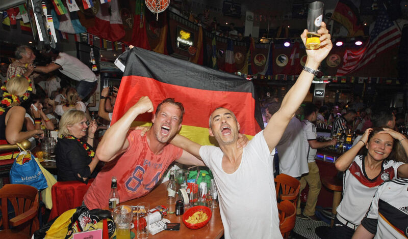 Begeisterte Fans gucken Fußball in einer Kneipe.