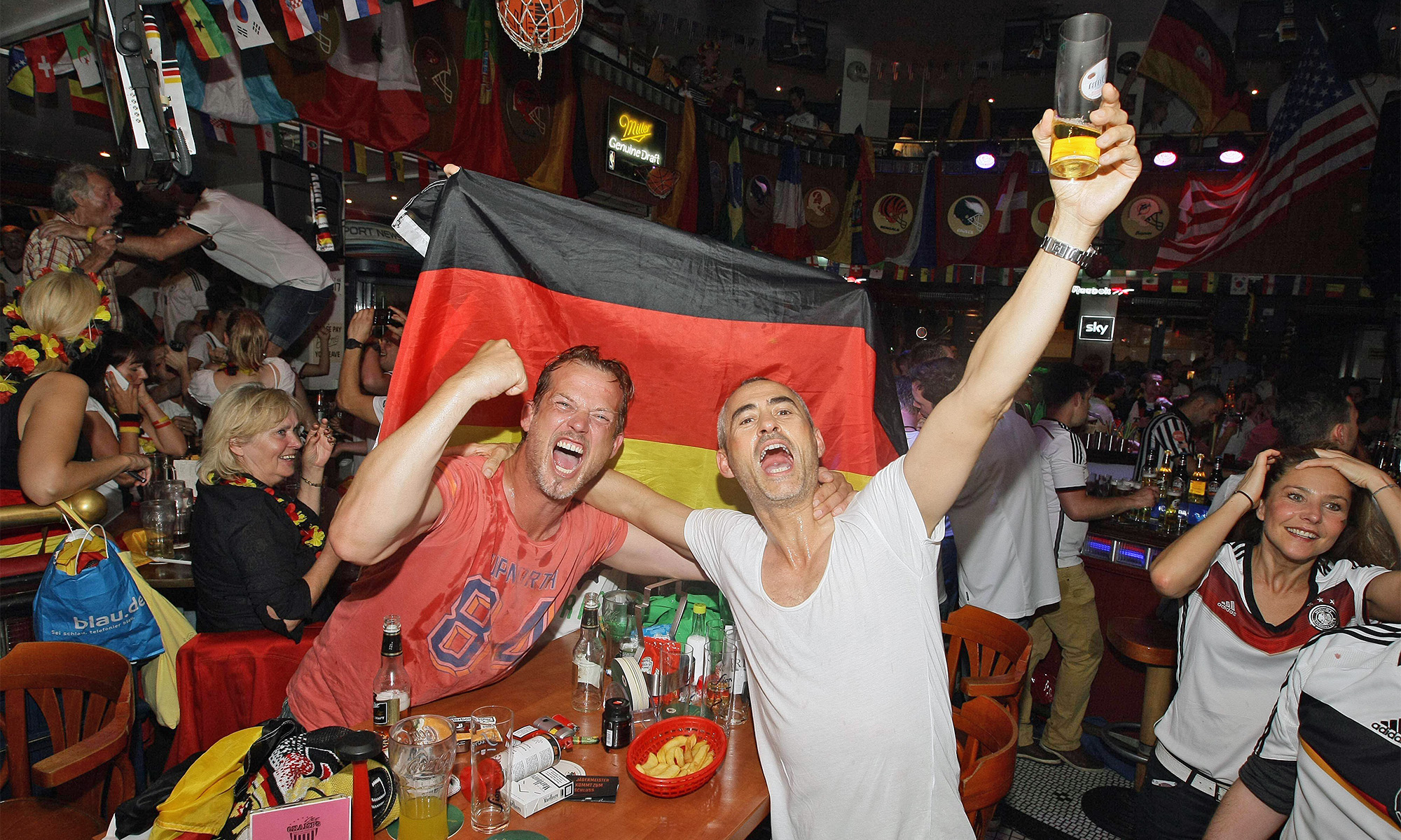 Begeisterte Fans gucken Fußball in einer Kneipe.