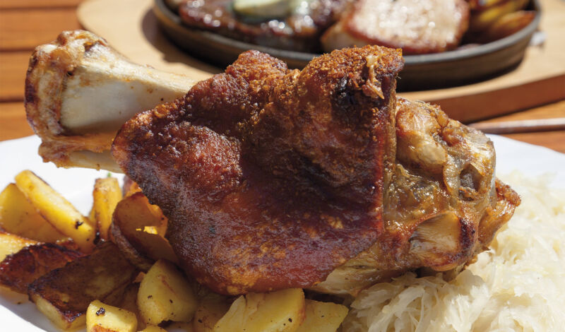 Eine gegrillte Schweinshaxe mit Bratkartoffeln.