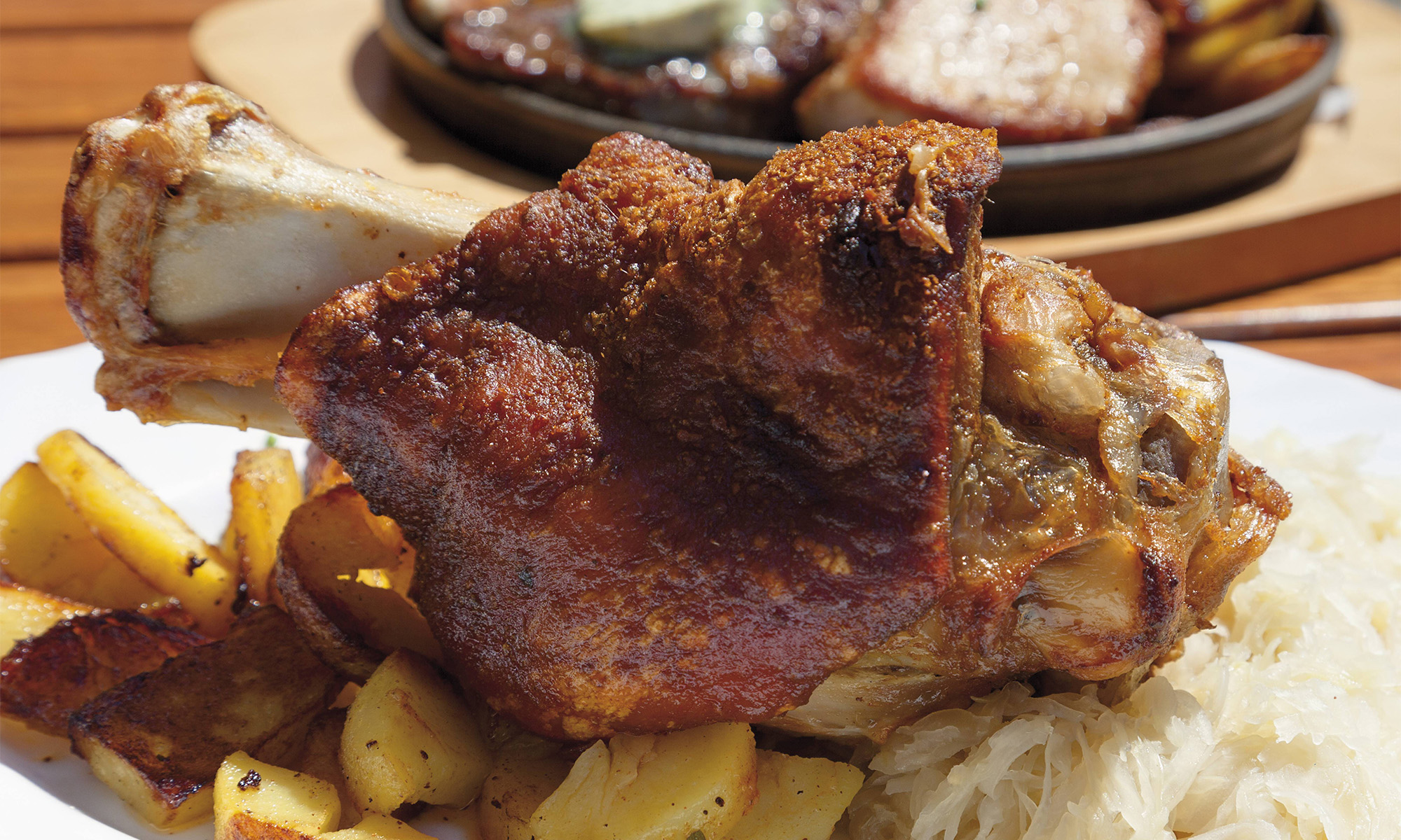Eine gegrillte Schweinshaxe mit Bratkartoffeln.