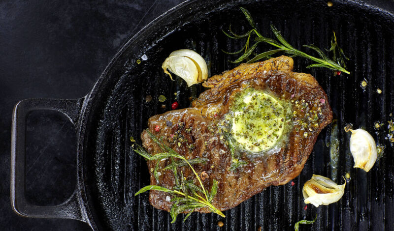 Ein Steak in einer Grillpfanne mit Kräuterbutter, Knoblauch