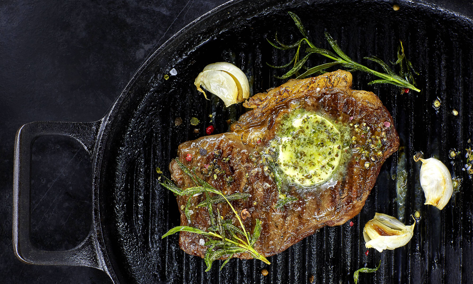 Ein Steak in einer Grillpfanne mit Kräuterbutter, Knoblauch
