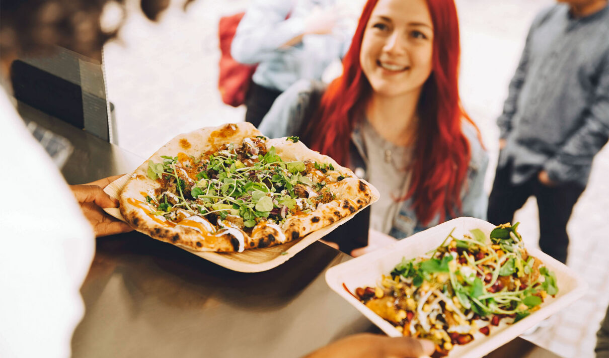 Eine Frau nimmt Snacks von einem Foodtruck entgegen.