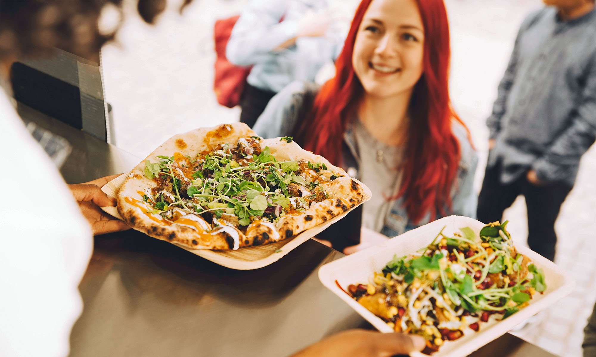 Eine Frau nimmt Snacks von einem Foodtruck entgegen.