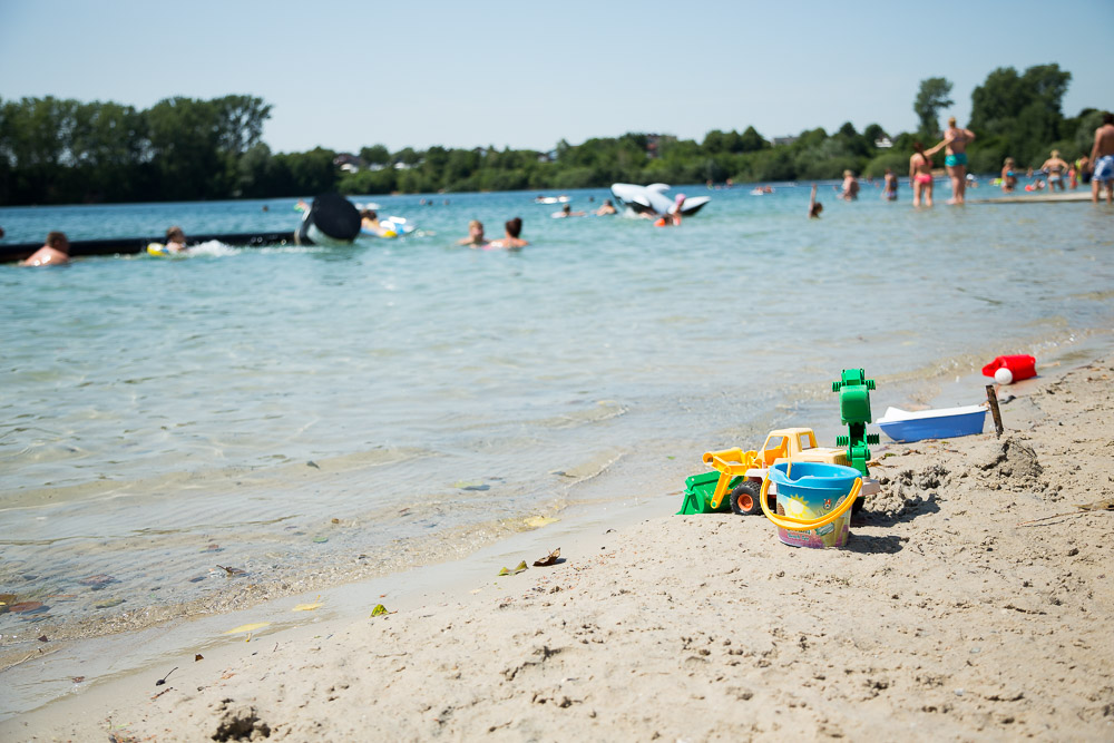 Sandstrand und badende Menschen am Escher See